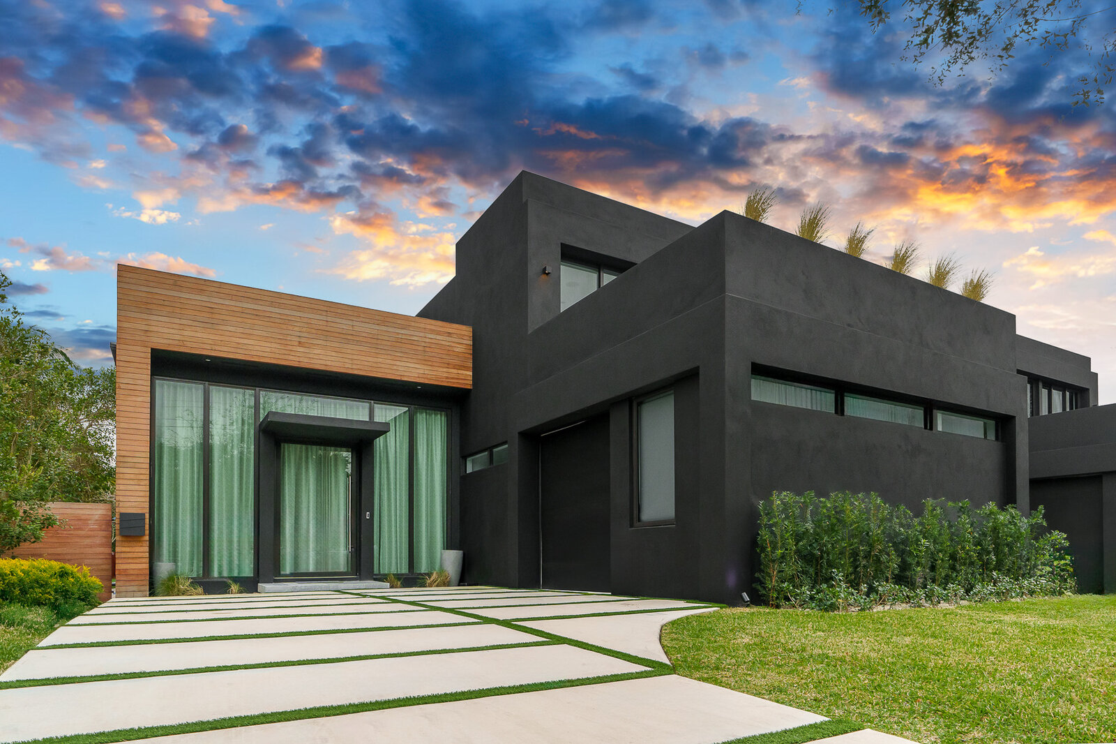 Contemporary black-and-wood home with a cotton-candy cirrus sunset